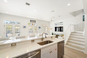A modern kitchen with a large island, built-in appliances, and a view to the outside. - All Decked Out – Elegant Seacrest Beach Home with Private Beach Access (Seacrest Beach)