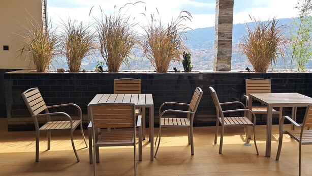Una terraza con mesa y sillas, vista a las montañas y plantas decorativas.