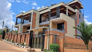 Una casa moderna de dos pisos con fachada de ladrillo, varios balcones y entrada con reja.