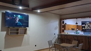 Una cocina moderna con barra, taburetes de madera y un televisor montado en la pared.