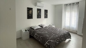 A bedroom with a bed, bedside tables, a window with curtains, and wall-mounted artwork. - The station (St Etienne De St Geoirs)