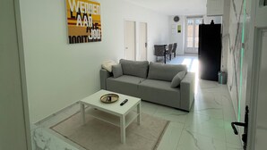 A modern living room with a grey sofa, a white coffee table, and a large artwork on the wall. - The station (St Etienne De St Geoirs)