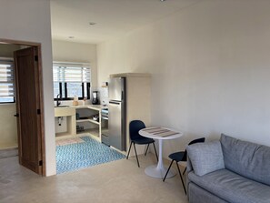Una cocina moderna con refrigerador, pileta y ventana. Hay un comedor con mesa y sillas.