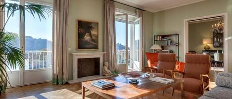 A spacious living room with a fireplace, comfortable seating, and large windows offering a view.