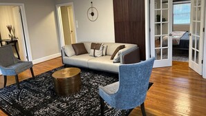 Ein modernes Wohnzimmer mit einer Couch, zwei Sesseln, einem Couchtisch und einem gemusterten Teppich.