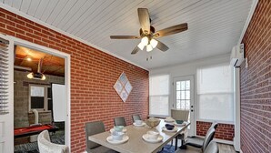 Ein Essbereich mit Backsteinwand, Deckenventilator und Tisch für vier Personen.