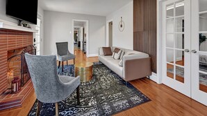 Ein modernes Wohnzimmer mit Kamin, einer Couch, einem Fernseher und einem Essbereich.