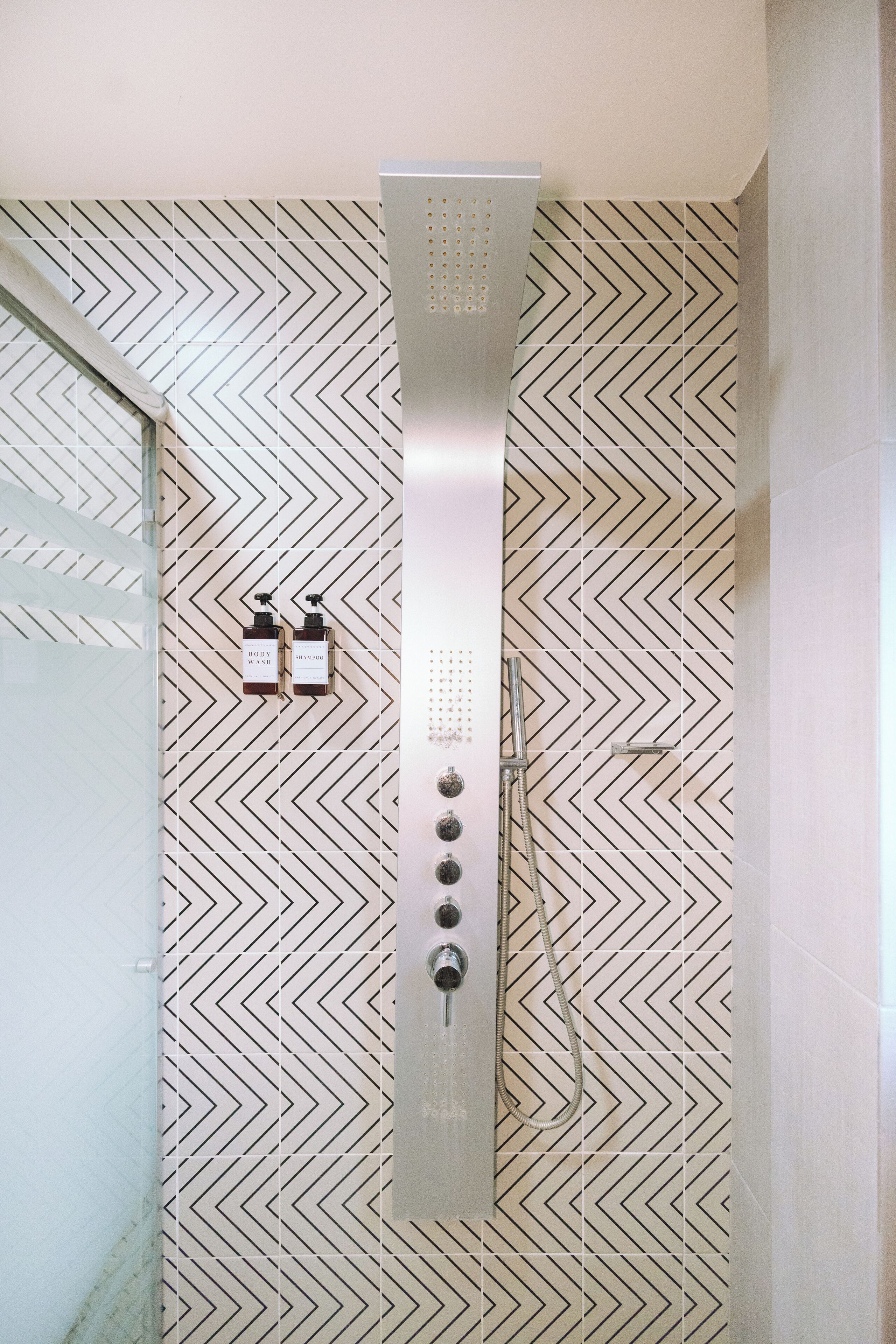 A shower with a modern design, featuring a control panel with multiple buttons and a handheld showerhead.