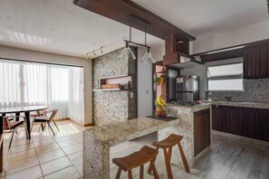 Eine moderne Küche mit Granitplatten, einem eingebauten Herd und einem Kühlschrank. Es gibt einen Essbereich mit einem runden Tisch und Stühlen.