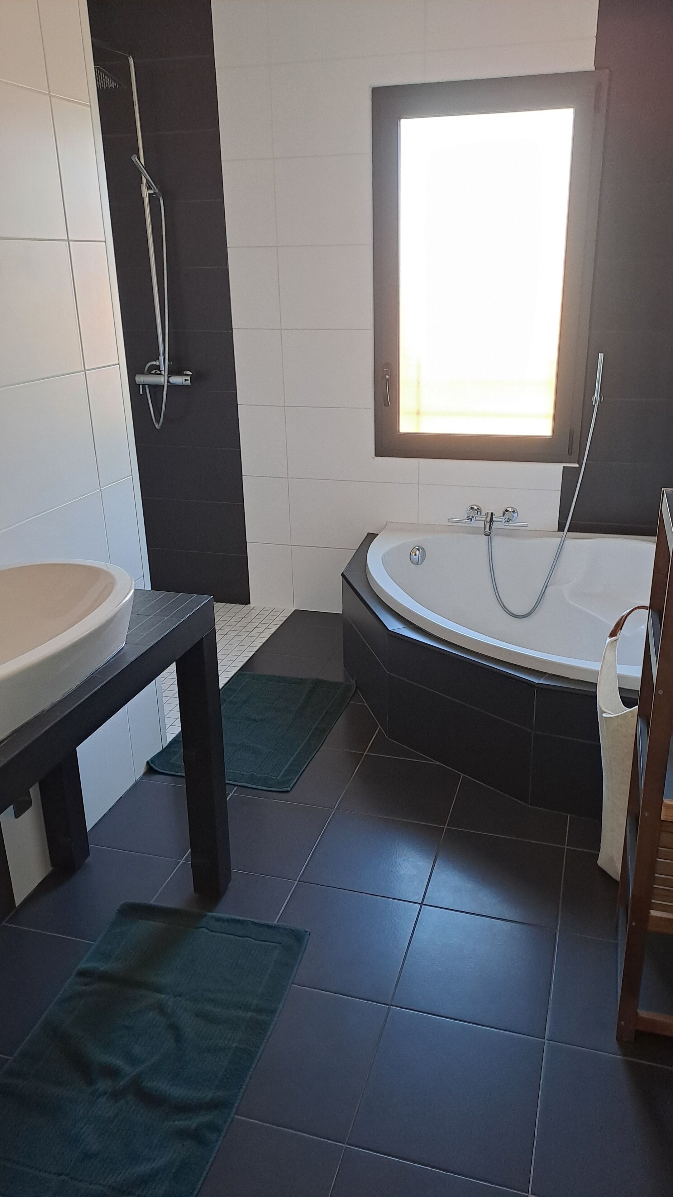 Une salle de bain moderne avec une baignoire, une grande fenêtre et une douche.