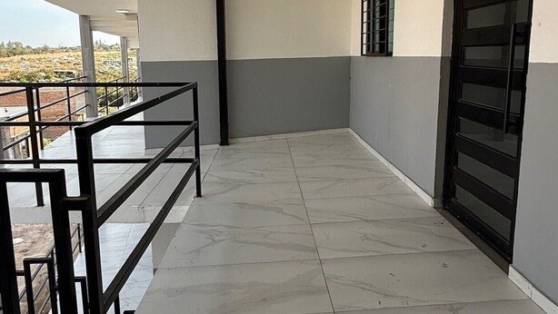 A spacious balcony with a tiled floor, a metal railing, and a large black door. - Residencia Gran Coyula Orange 512B (Tonala)