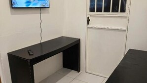 A room with a black table, a white door, and a television mounted on the wall.