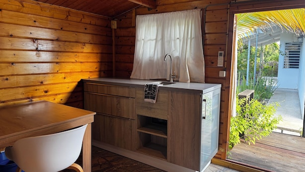 A compact kitchen with wooden walls, a sink, and a small countertop. - Garden Studio Retreat (Sint Michiel)