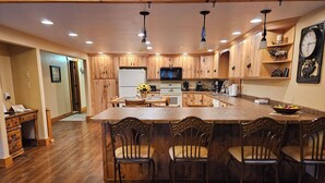 A spacious kitchen with wooden cabinets, a central island with bar stools, a microwave, and a refrigerator.
