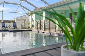 A pool area with a covered section, lounge chairs, and a potted plant.