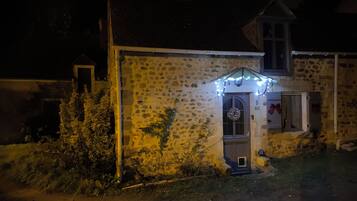 Un bâtiment en pierre avec un petit porche, une porte ornée d’une guirlande et le chiffre « 5 » au-dessus de la porte.