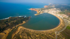 Luftaufnahme einer Küstenregion mit einer großen Bucht, einem Strand und einer Stadt mit Gebäuden entlang der Küste.