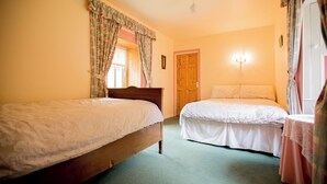 A bedroom with two single beds, a wooden door, and a wall-mounted light fixture. - Beautiful 200 year old thatched cottage in the picturesque village of Adare (Adare)