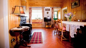A wooden interior with a fireplace, television, dining table, and chairs. - Beautiful 200 year old thatched cottage in the picturesque village of Adare (Adare)