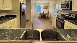 A kitchen with marble countertops, a double sink, a refrigerator, a microwave, and a dining area with a table and chairs. - Country Lake Getaway. (Summit)