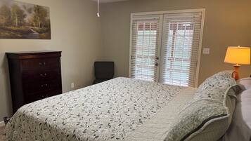 A bedroom with a bed, a dresser, a ceiling fan, and a window with blinds.