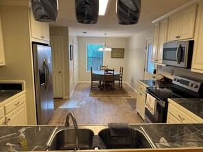 A kitchen with a refrigerator, microwave, stove, and sink.