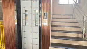 A staircase leading to an elevator with a metallic handrail and a glass door. - Wren Hideaway:Cozy AC Studio in Pune (Pimpri-Chinchwad)