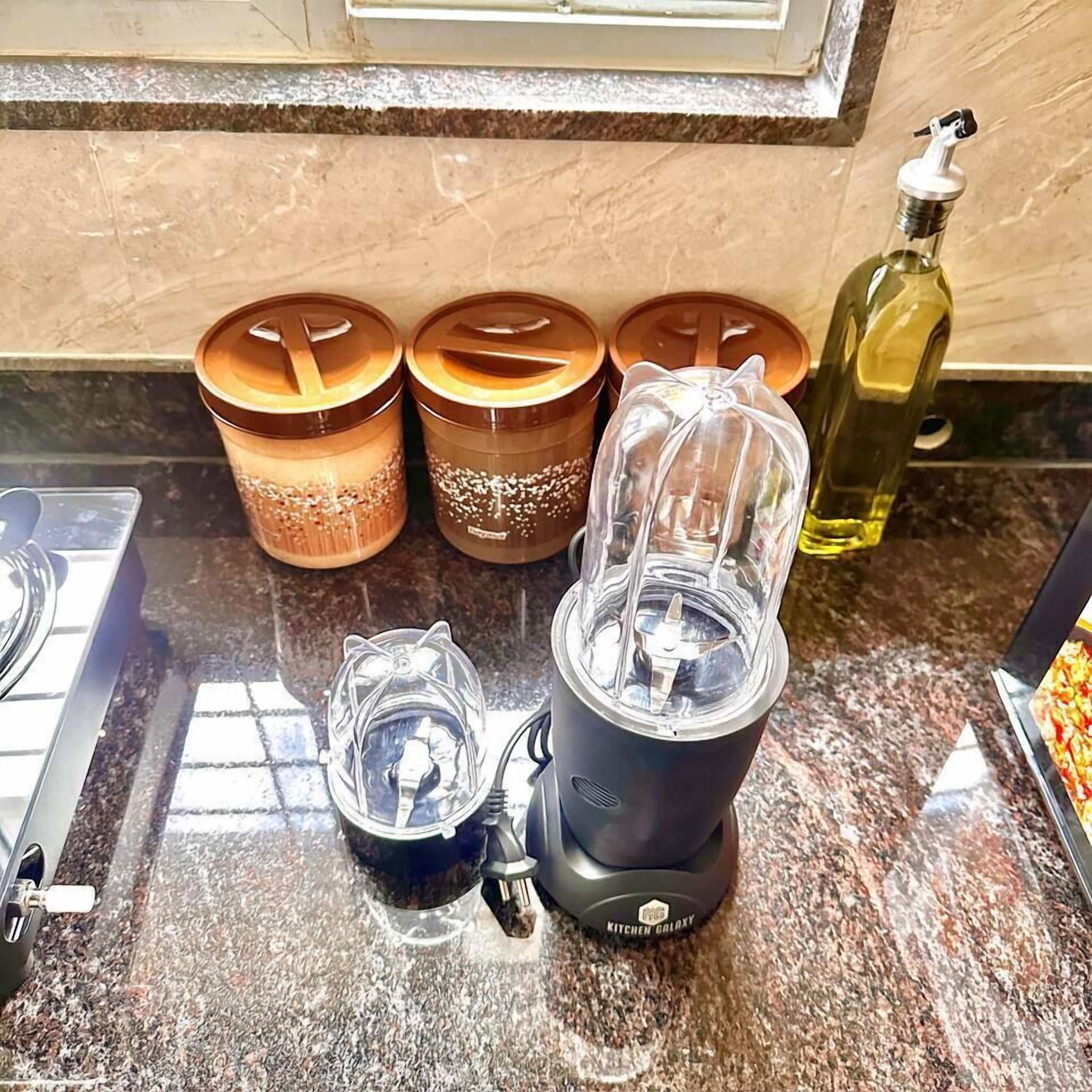 A kitchen counter with a blender, two spice jars, a pepper grinder, and a bottle of oil.