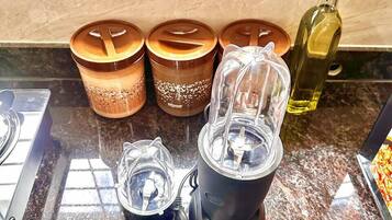 A kitchen counter with a blender, two spice jars, a pepper grinder, and a bottle of oil.