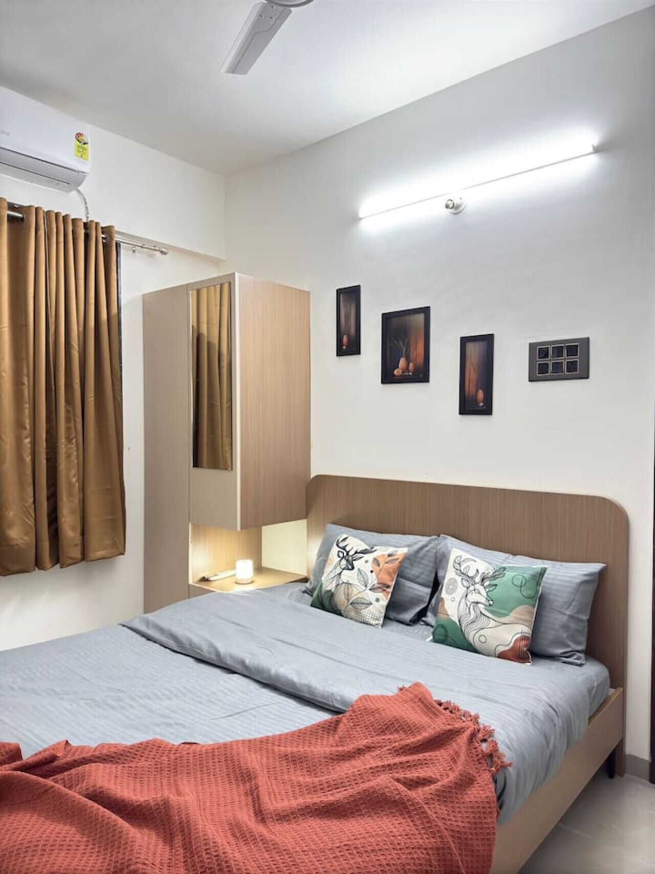 A bedroom with a bed, a nightstand, a mirror, and a wall-mounted air conditioner.