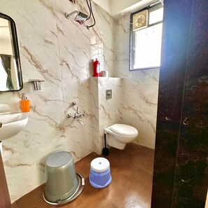 A bathroom with a marble wall, a toilet, a sink, and a shower.
