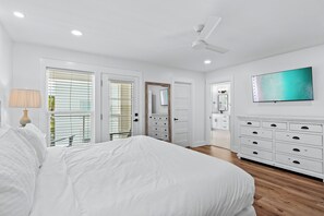 A bedroom with a large bed, white walls, a ceiling fan, a TV, and a dresser. - Beach Music Gorgeous 6 Bdrm, steps to beach, 6 seater golf cart (Santa Rosa Beach)