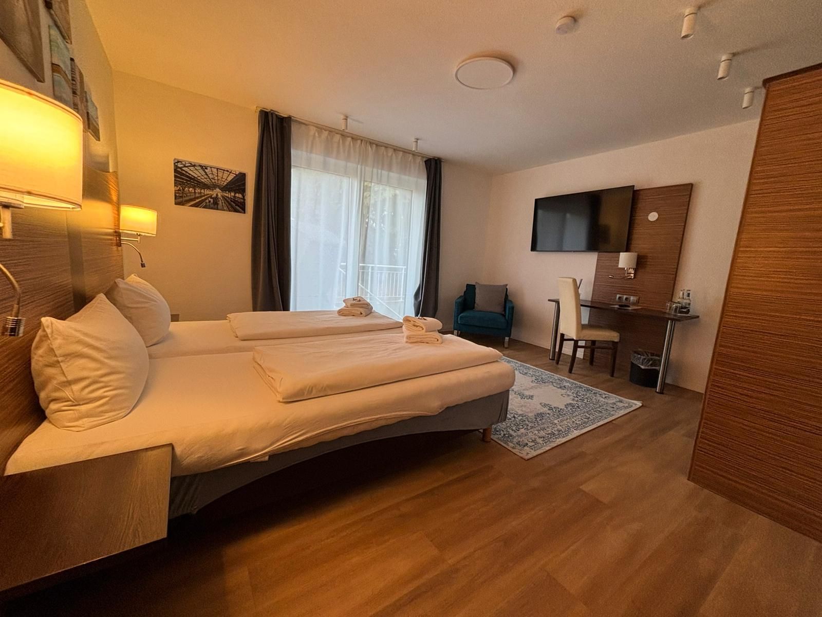 Hotellihuone, jossa on sänky, työpöytä, tuoli, televisio ja kylpyhuone.