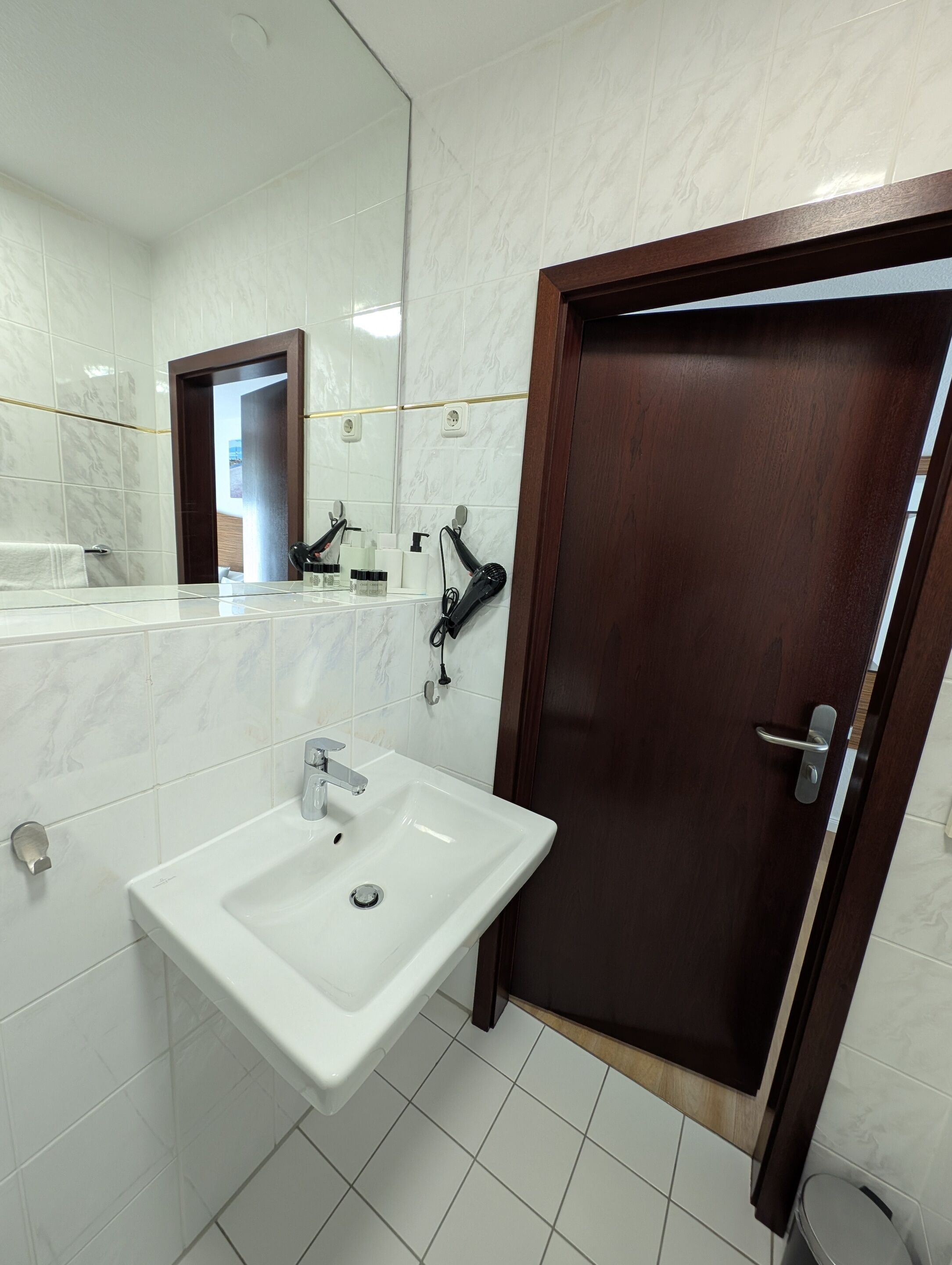 A bathroom with a white sink, a mirror, and a wooden door.