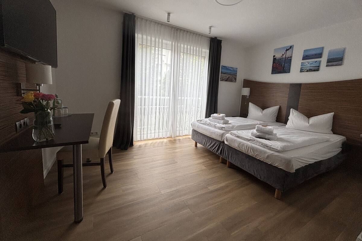 A hotel room with a bed, a desk, a chair, and a TV.