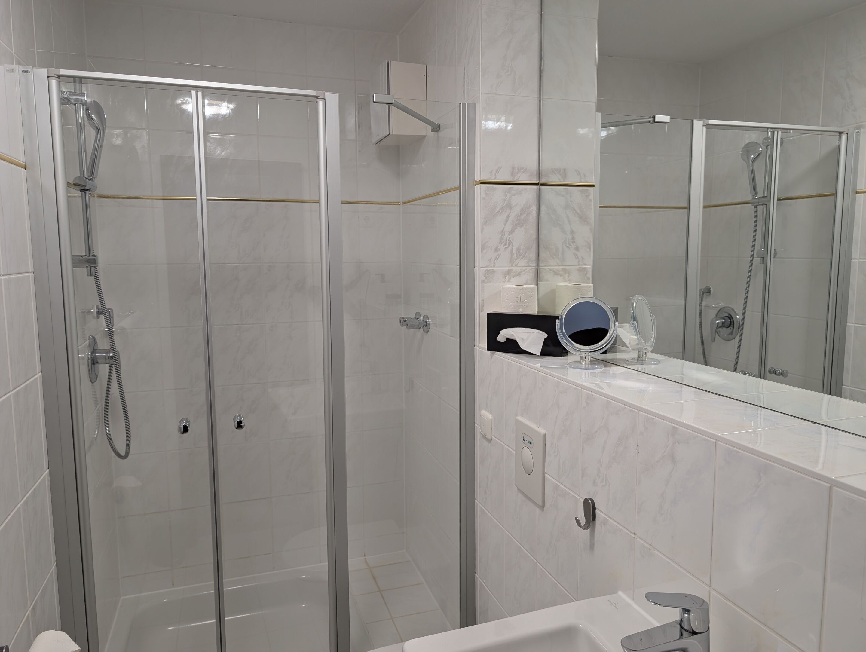 Ein modernes Badezimmer mit einer einteiligen Duschkabine, einem Waschtisch mit Spiegel und einer Toilette.