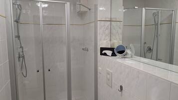 Ein modernes Badezimmer mit einer einteiligen Duschkabine, einem Waschtisch mit Spiegel und einer Toilette.