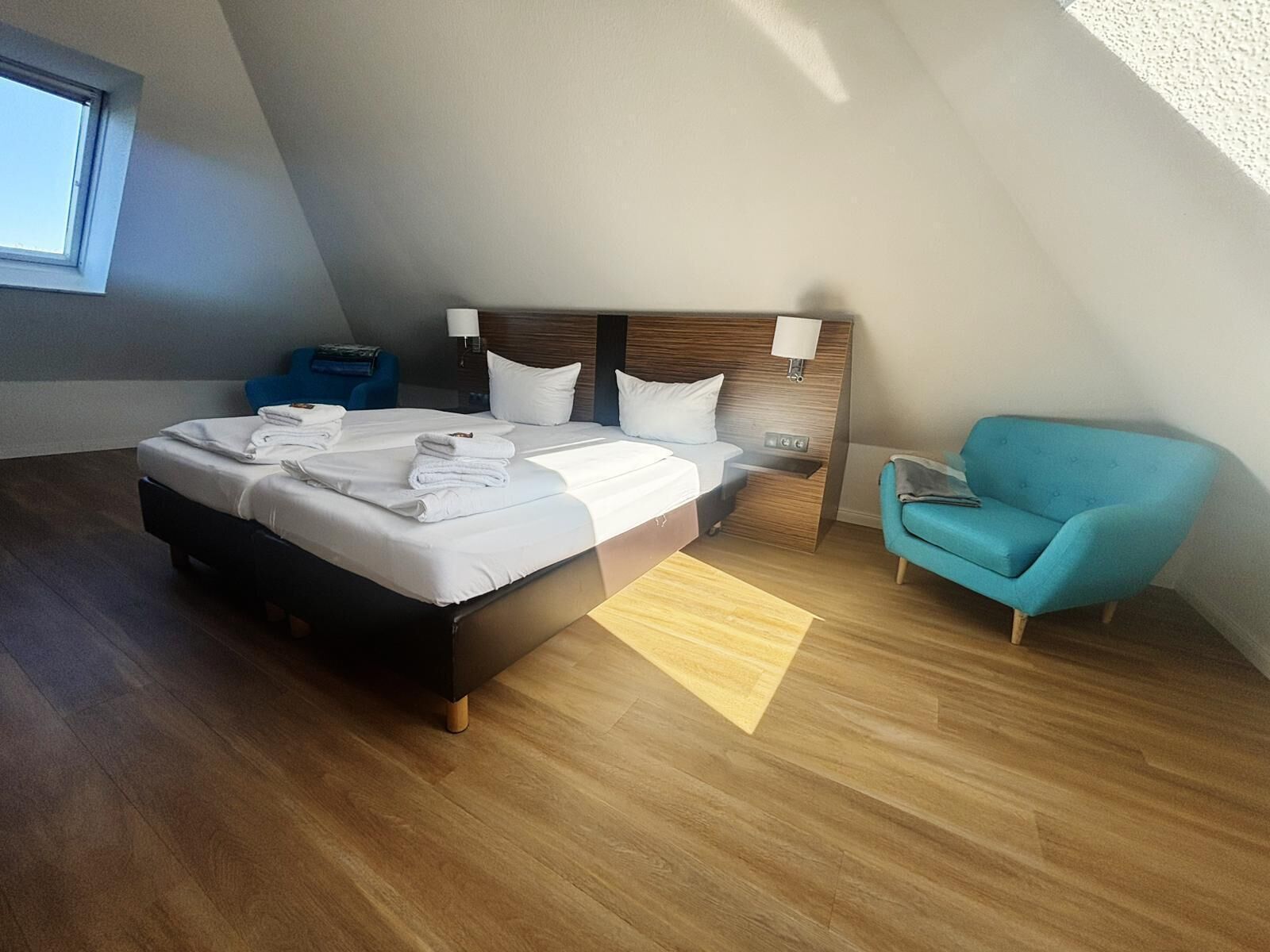 Une chambre d’hôtel moderne avec un grand lit, une table de chevet, une chaise et une fenêtre.