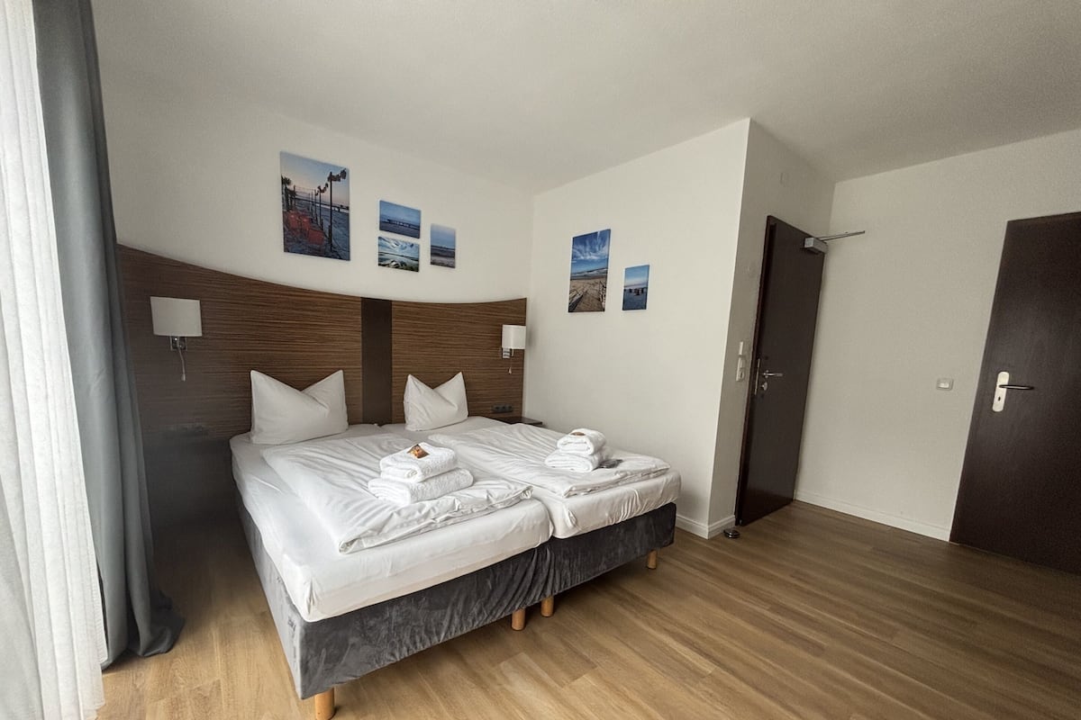 A hotel room with a double bed, two bedside tables, a headboard, and a door.