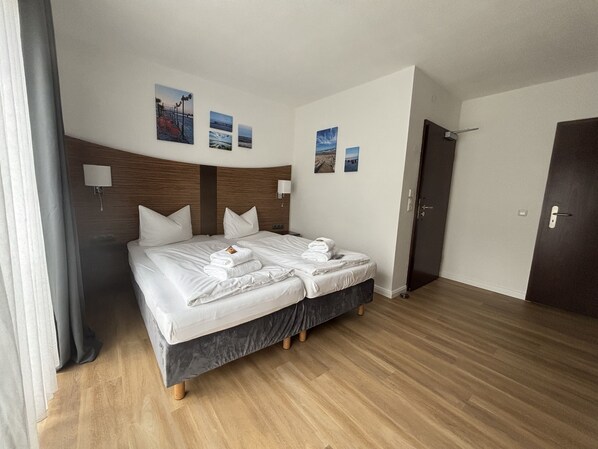 A hotel room with a double bed, two bedside tables, a headboard, and a door. - Turmhotel Scharbeutz (Scharbeutz)