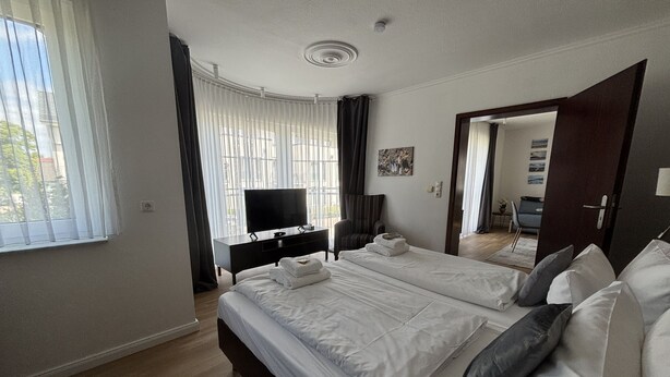 A hotel room with a large bed, a TV, a desk, and a chair. - Turmhotel Scharbeutz (Scharbeutz)
