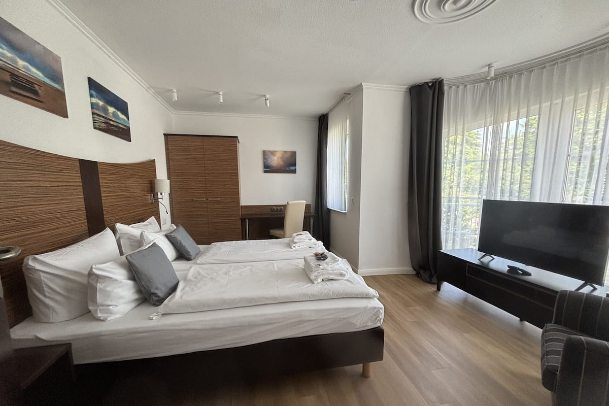 A modern hotel room with a large bed, a TV, and a desk.