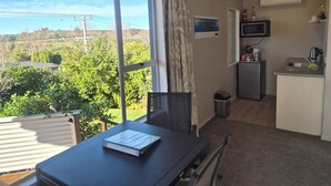 Una habitación con un ventanal grande, una mesa con un libro, una kitchenette y vistas a zonas verdes.