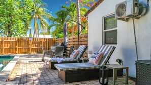 A poolside area with lounge chairs, a table, and a grill. - Pool House in Fort Lauderdale (Fort Lauderdale)
