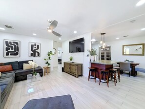 A modern living room with a sofa, a coffee table, and a dining area with stools. - Pool House in Fort Lauderdale (Fort Lauderdale)