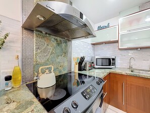 A modern kitchen with a black stovetop, a microwave, a kettle, and a toaster. - Pool House in Fort Lauderdale (Fort Lauderdale)