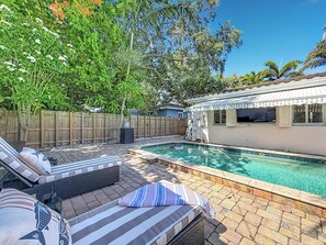 Un jardin avec une piscine, des chaises longues et une clôture en bois.
