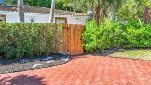 A residential property with a brick driveway, a wooden gate, and lush greenery. - Pool House in Fort Lauderdale (Fort Lauderdale)