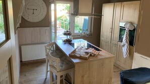 Una cocina con una isla de madera, un reloj en la pared y una ventana con vistas a un jardín.