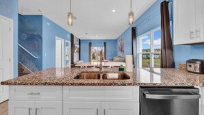 A modern kitchen with granite countertops, stainless steel appliances, and a view of the outdoors. - Comfortable 4 bedroom 4 bath Home Near Disney (Davenport)